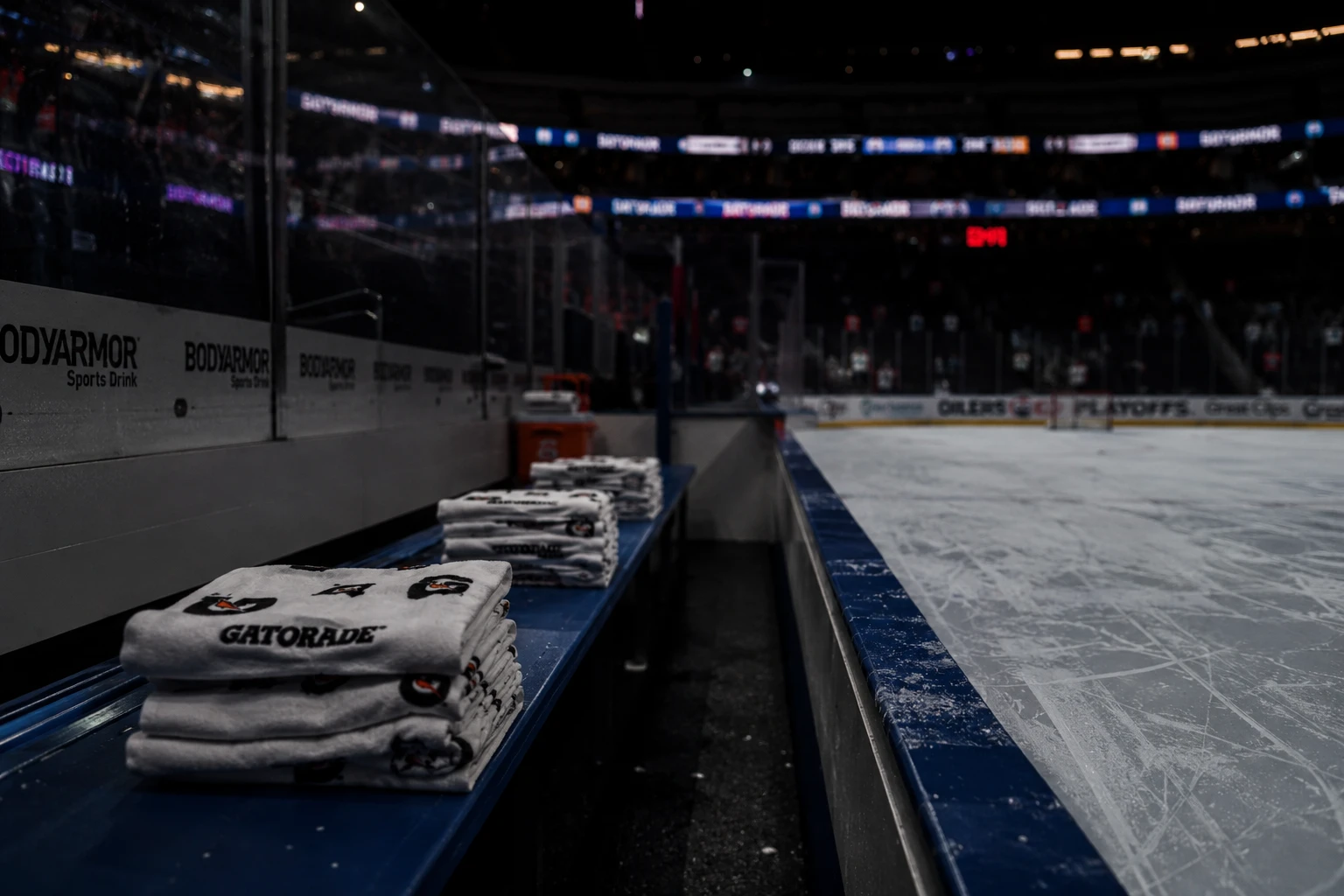 NHL 경기 후 벤치 끝에 정리된 타월과 흐릿한 링크 조명이 남아 있는 장면